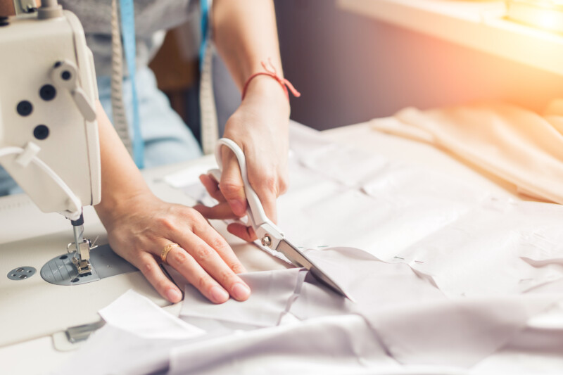 Woman cutting crepe fabric on a sewing table.