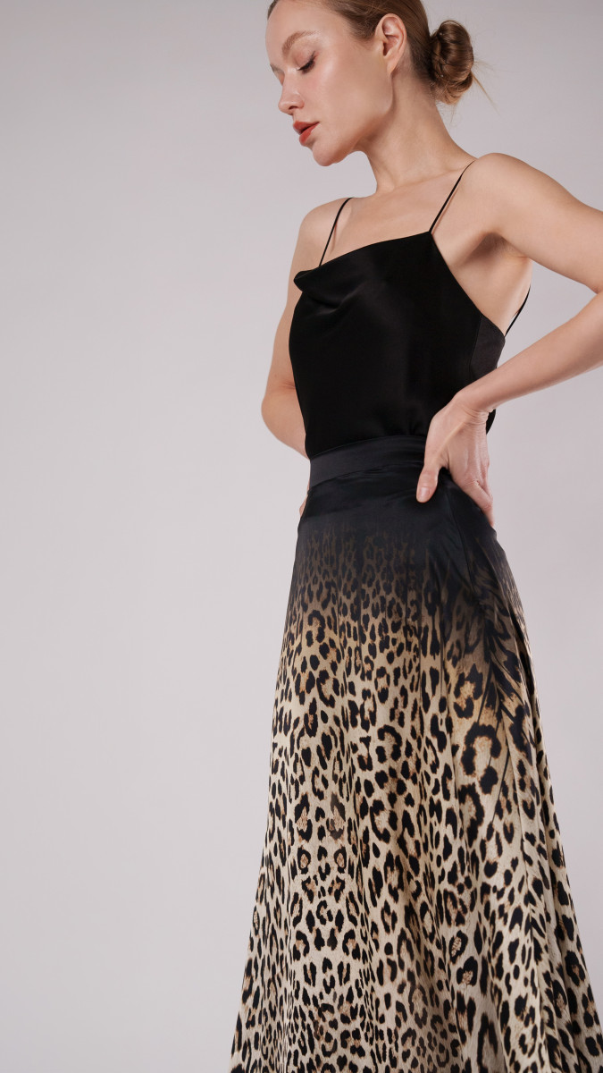 Model wearing Fiera Maxi Skirt free sewing pattern from Mood Fabrics Sewciety blog, featuring a sleek black camisole and leopard print satin skirt. | Fiera Maxi Skirt Free Sewing Pattern - Leopard Printed Silk Charmeuse Fashion Fabric - Model Photo Side View - MDF416 - Mood Fabrics Sewciety Blog