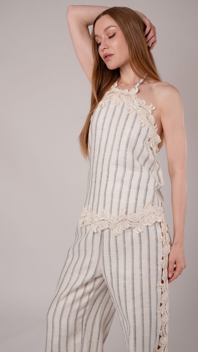 Model posing with arm behind her head wearing a heavy linen twill set with venise lace trim