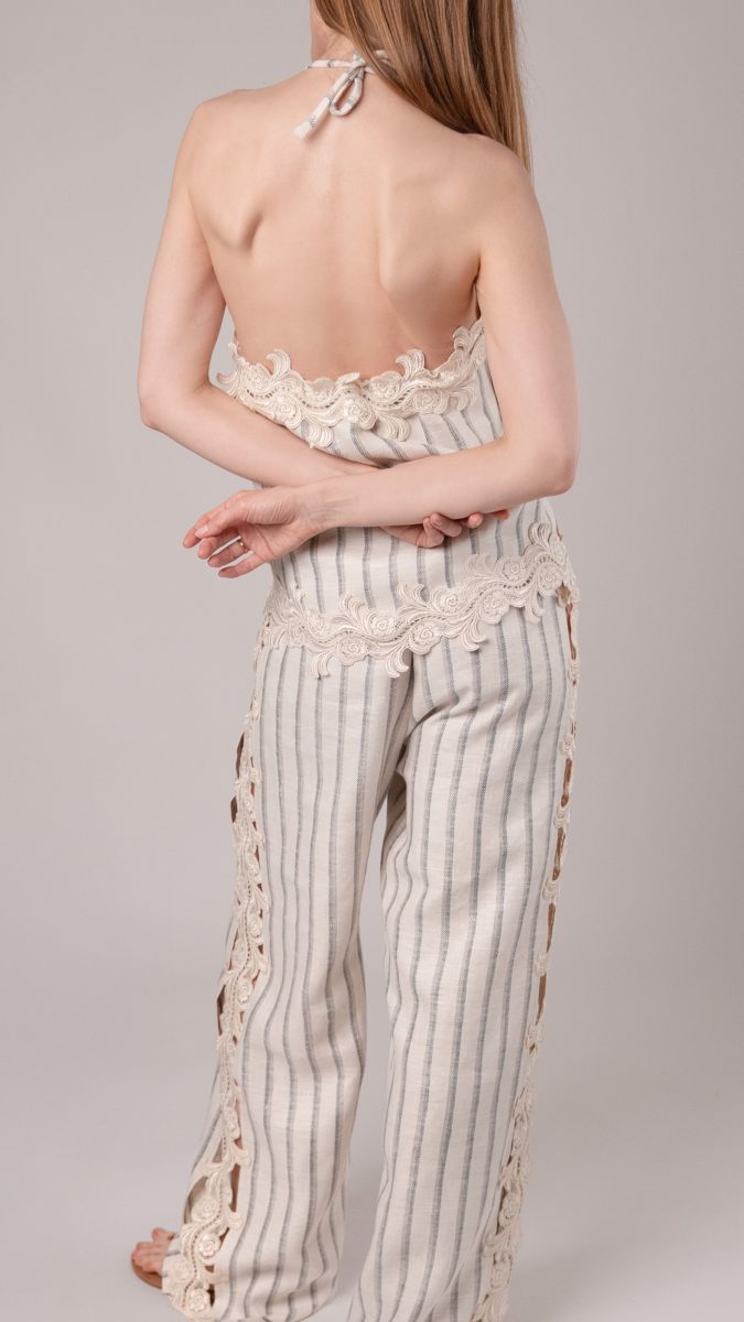 Back view of female model posing with her arms crossed behind her back wearing a striped matching set in heavy linen twill and venise lace trim