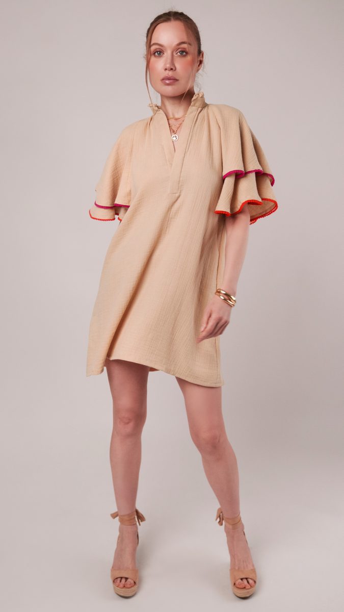 Front view of model posing with a double cotton gauze A-line dress, wedge heels, and gold jewelry