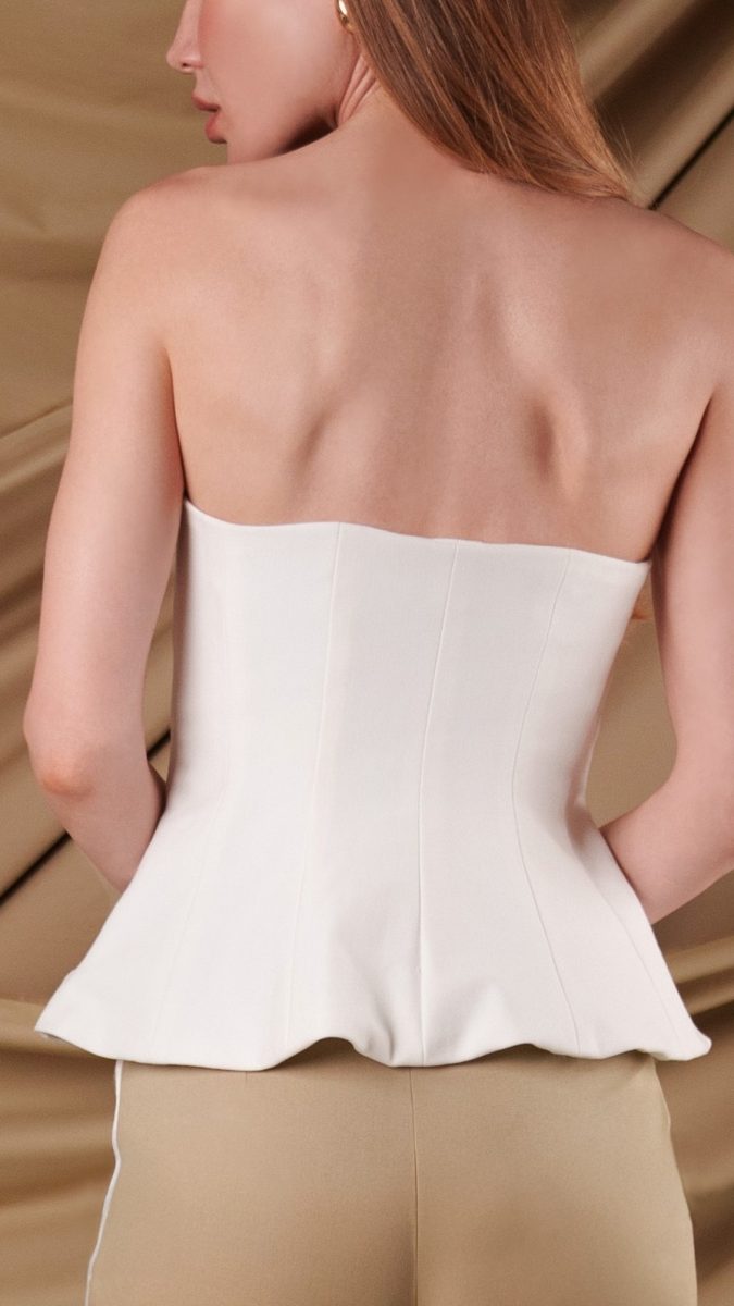 Closeup back view of model wearing white peplum blouse made from stretch ponte knit fashion fabric