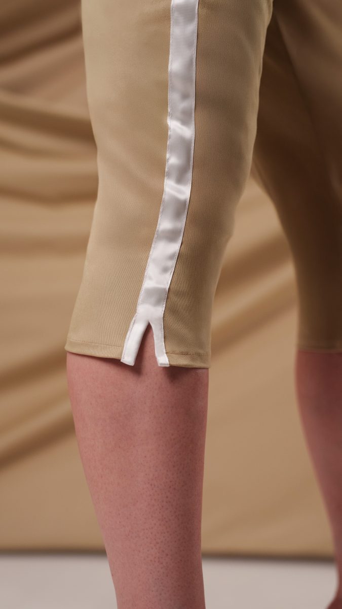 Close up side view of model wearing capris pants made from khaki twill and white ribbon trim