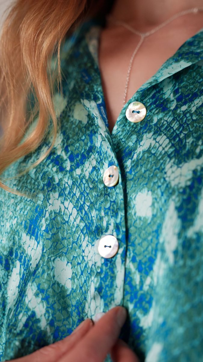 Detail of The Pirouette Luxe Set showing mother-of-pearl statement buttons on royal and jade python silk charmeuse top, luxury finish and tailored design, Mood Fabrics Sewicety Blog.