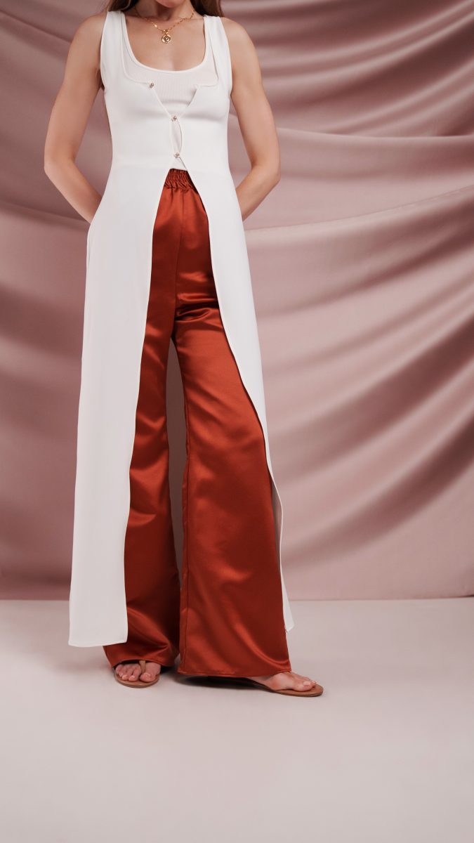 Model wearing Topanga Ensemble free sewing pattern from the Mood Fabrics Sewciety blog, styled with a white stretch polyester crepe top featuring pearl button details and rust satin wide-leg pants.