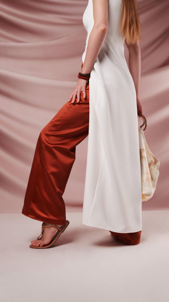 Side view of The Topanga Ensemble free sewing pattern from the Mood Fabrics Sewciety blog, featuring a long white crepe sleeveless top styled with rust satin wide-leg pants.