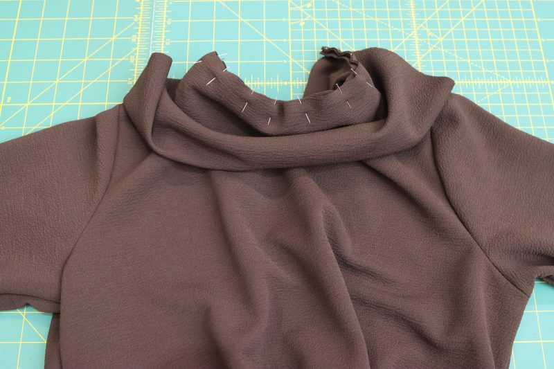 How-To-Pin-Collar-to-Neck-Opening-Dark Chocolate Stretch Polyester Crepe Knit--Mood-Fabrics Pin the raw edge of the collar to the raw edge of the neck opening.