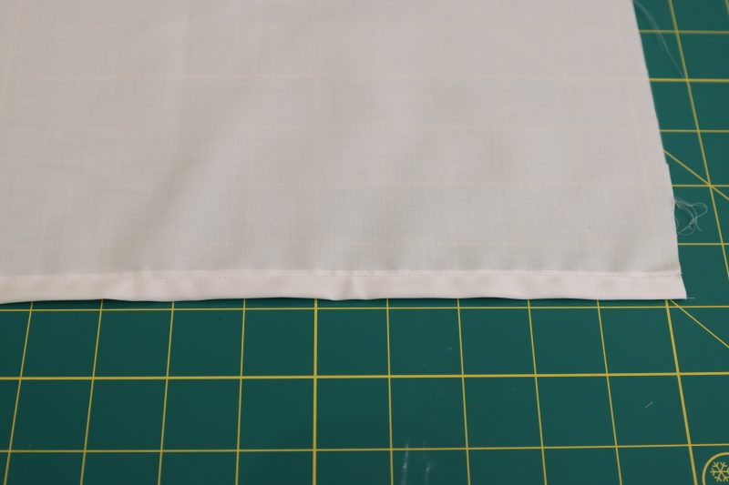 How To Sew Folded Hem - Egyptian Cotton Shirting Optic White Giza Collection - Mood Fabrics - Oxford Pleated Skirt and Tie Free Sewing Pattern Tutorial - MDF460 - Mood Fabrics Sewciety Blog - Sew along the upper folded edge of the hem to secure it in place.