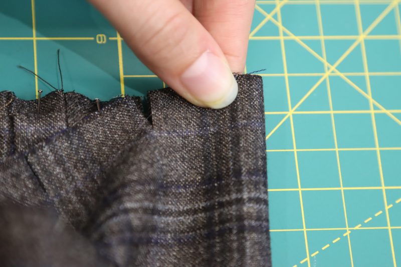 How To Fold Space Between Notches in Half - Super 130s Wool Twill Suiting Made in Italy Charcoal Gray Navy Plaid Deadstock - Mood Fabrics - Oxford Pleated Skirt and Tie Free Sewing Pattern Tutorial - MDF460 - Mood Fabrics Sewciety Blog - Fold the space between the two notches in half, right sides together.
