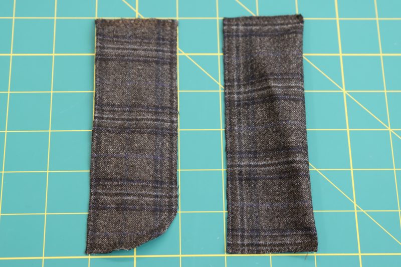 How To Sew Zigzag Along Edges Of Fly Pieces - Super 130s Wool Twill Suiting Made in Italy Charcoal Gray Navy Plaid Deadstock - Mood Fabrics - Oxford Pleated Skirt and Tie Free Sewing Pattern Tutorial - MDF460 - Mood Fabrics Sewciety Blog - Sew a zigzag stitch around the raw edges of the fly facing and shield.