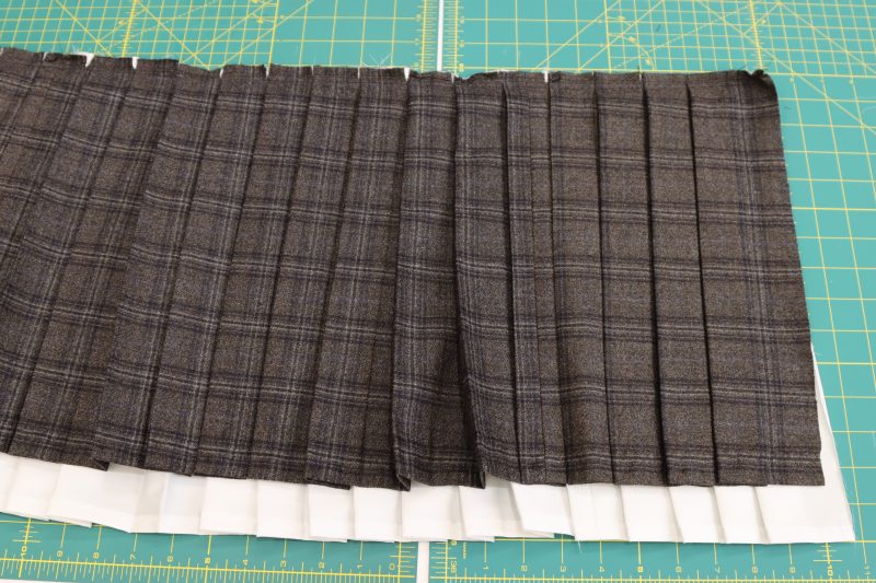 How To Align Sew Straight Stitch Across Inner Skirt and Shell - Super 130s Wool Twill Suiting Made in Italy Charcoal Gray Navy Plaid Deadstock - Mood Fabrics - Oxford Pleated Skirt and Tie Free Sewing Pattern Tutorial - MDF460 - Mood Fabrics Sewciety Blog - Sew a straight stitch across the waistbands of the skirts to attach the inner skirt to the shell.