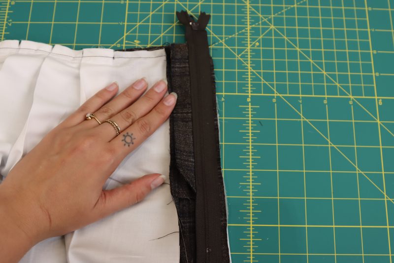 How To Place Zipper Right Sides Together with Skirt Center Seam - Regular Zipper 9 Inch YKK 916 After Dark - Mood Fabrics - Oxford Pleated Skirt and Tie Free Sewing Pattern Tutorial - MDF460 - Mood Fabrics Sewciety Blog - Place the rightmost side of the zipper right sides together on top of the right center seam of the skirt.