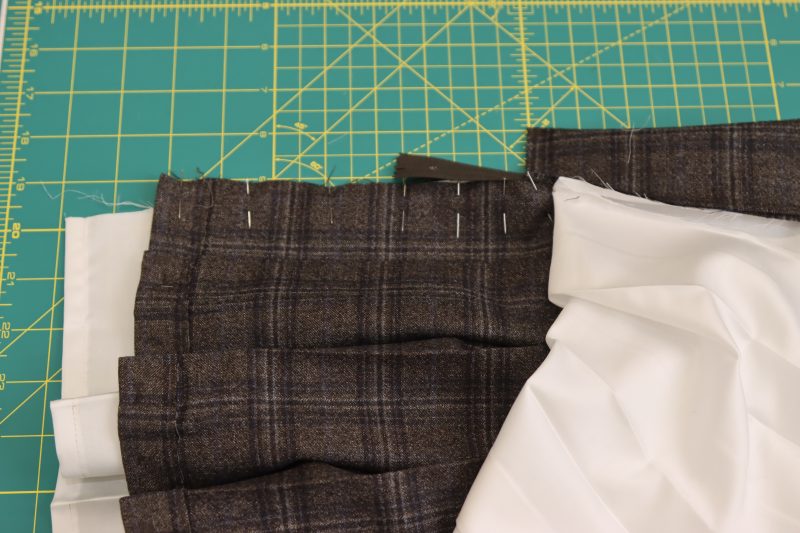 How To Pin Front Center Seam Of Skirt Together - Super 130s Wool Twill Suiting Made in Italy Charcoal Gray Navy Plaid Deadstock - Mood Fabrics - Oxford Pleated Skirt and Tie Free Sewing Pattern Tutorial - MDF460 - Mood Fabrics Sewciety Blog - Pin the front center seam of the skirt shell right sides together.