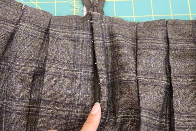 How To Sew Top Stitch Down Fly Facing - Super 130s Wool Twill Suiting Made in Italy Charcoal Gray Navy Plaid Deadstock - Mood Fabrics - Oxford Pleated Skirt and Tie Free Sewing Pattern Tutorial - MDF460 - Mood Fabrics Sewciety Blog - Sew a top stitch down the front of the skirt over the seam that connects the fly facing to the front of the skirt.