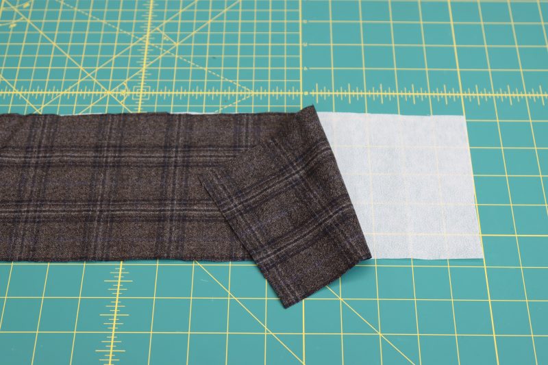 How To Iron Fusible Interfacing To Waistband - Non Woven Single Side Fusible Interfacing - Mood Fabrics - Oxford Pleated Skirt and Tie Free Sewing Pattern Tutorial - MDF460 - Mood Fabrics Sewciety Blog - Iron the fusible interfacing to the wrong side of the waistband.
