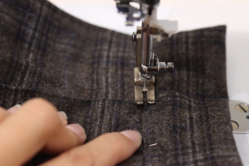 How To Sew Stitch in the Ditch Waistband - Super 130s Wool Twill Suiting Made in Italy Charcoal Gray Navy Plaid Deadstock - Mood Fabrics - Oxford Pleated Skirt and Tie Free Sewing Pattern Tutorial - MDF460 - Mood Fabrics Sewciety Blog - Sew a stitch right on top of the outer seam of the waistband, creating a “stitch in the ditch”.