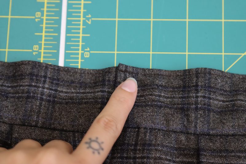 How To Topstitch Waistband Over Belt Loops - Super 130s Wool Twill Suiting Made in Italy Charcoal Gray Navy Plaid Deadstock - Mood Fabrics - Oxford Pleated Skirt and Tie Free Sewing Pattern Tutorial - MDF460 - Mood Fabrics Sewciety Blog - Sew a topstitch ⅛ inch away from the top of the waistband, sewing over the tops of the beltloops.