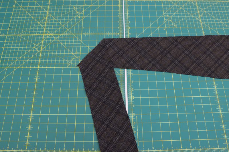 How To Sew Inside Ends Of Tie Pieces - Super 130s Wool Twill Suiting Made in Italy Charcoal Gray Navy Plaid Deadstock - Mood Fabrics - Oxford Pleated Skirt and Tie Free Sewing Pattern Tutorial - MDF460 - Mood Fabrics Sewciety Blog - Sew the two inside ends of the ties pieces right sides together at the diagonal end.