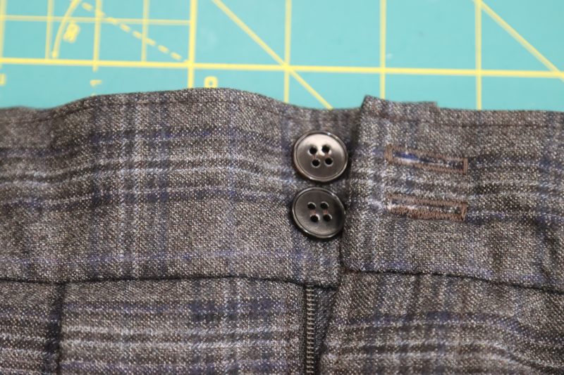 How To Sew Buttons By Hand - 24L Chocolate Horn 4 Hole Button - Mood Fabrics - Oxford Pleated Skirt and Tie Free Sewing Pattern Tutorial - MDF460 - Mood Fabrics Sewciety Blog - Hand sew the buttons to the other side of the waistband to fit into the buttonholes.