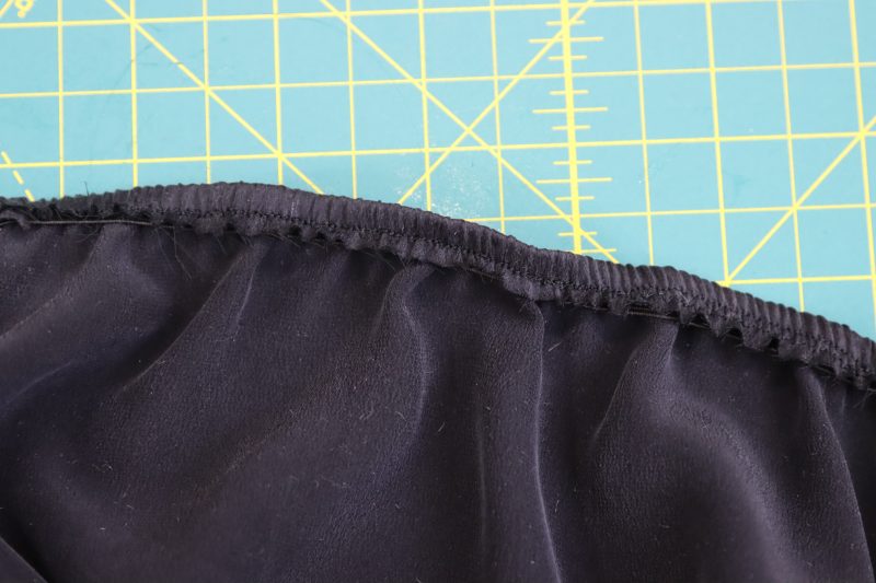 How To Fold Top Back Edge - Washed Silk Charmeuse 19mm Black - Mood Fabrics - Odette Nightgown Free Sewing Pattern Tutorial - MDF462 - Mood Fabrics Sewciety Blog - Fold over the top back edge and topstitch to hide the elastic.