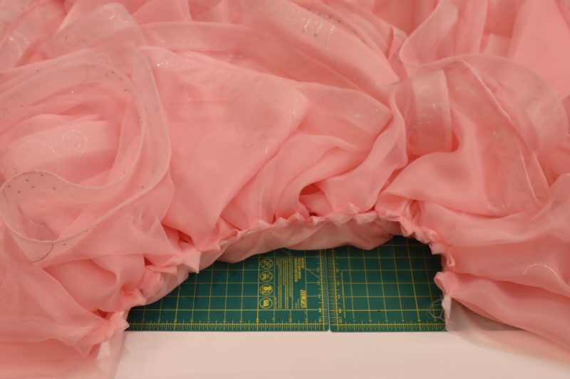 How To Pin Sew Overskirt Ruffles To Lining - Satin Faced Organza - Mood Fabrics - Glinda Gown Free Sewing Pattern Tutorial - MDF463 - Mood Fabrics Sewciety Blog - Pin and sew the overskirt ruffles in between the underskirt ruffles on the skirt lining.