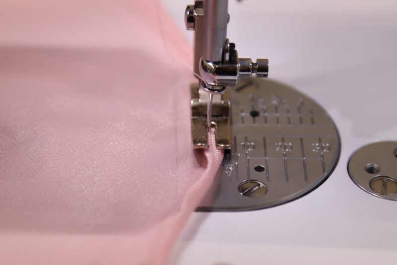 How To Fold Serged Edge Of Overlay - Organza - Mood Fabrics - Glinda Gown Free Sewing Pattern Tutorial - MDF463 - Mood Fabrics Sewciety Blog - Fold the serged edge over and top stitch.