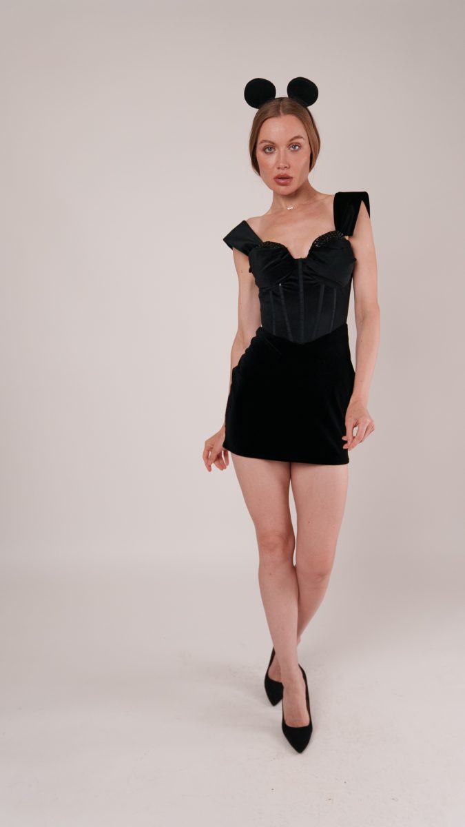 Model wearing the Ambrosia Cocktail Dress styled as a Mean Girls–inspired “I’m a Mouse, Duh” Halloween costume. The sleek black mini dress is paired with black mouse ears and classic pumps for a fun, instantly recognizable look.