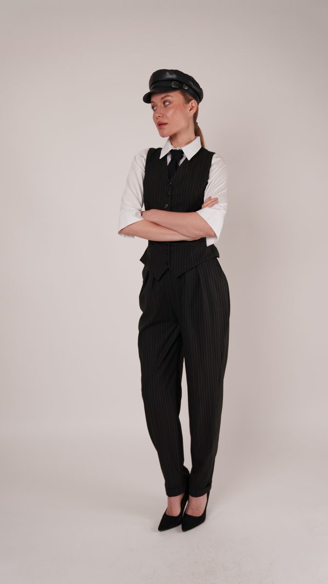 Model in Anne Waistcoat Ensemble with arms crossed, wearing a fitted pinstripe vest and trousers, channeling vintage gangster and Peaky Blinders costume inspiration.