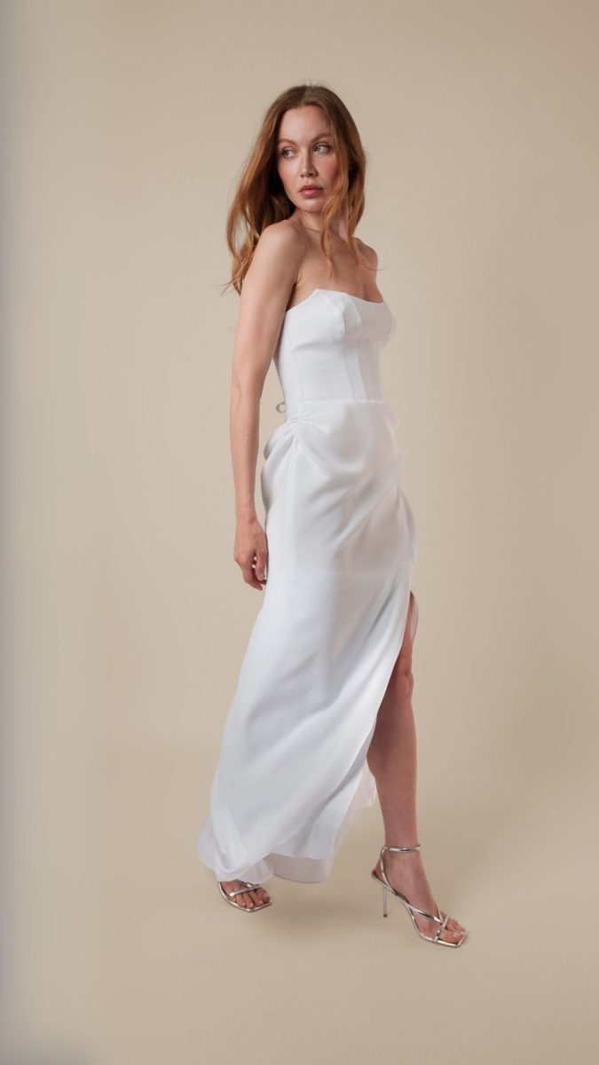 Model wearing the London Gown, a strapless white costume dress with a sleek fit and thigh-high slit, styled with silver strappy heels — Taylor Swift-inspired costume idea.
