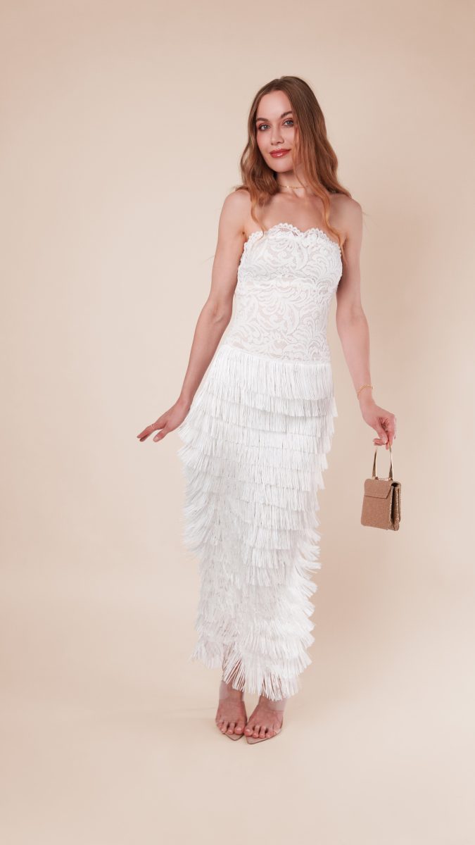 Woman in a strapless white lace gown with a tiered fringe skirt and gold handbag, styled as a 1920s flapper costume idea using the Lumiere Strapless Dress free sewing pattern.
