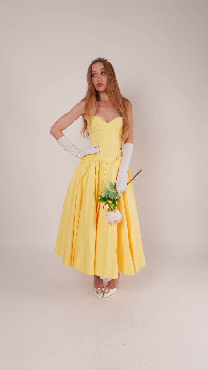 Woman in a yellow strapless gown with gloves and tiara, holding a rose, styled as a Belle from Beauty and the Beast costume idea using the Madison Dress free sewing pattern.