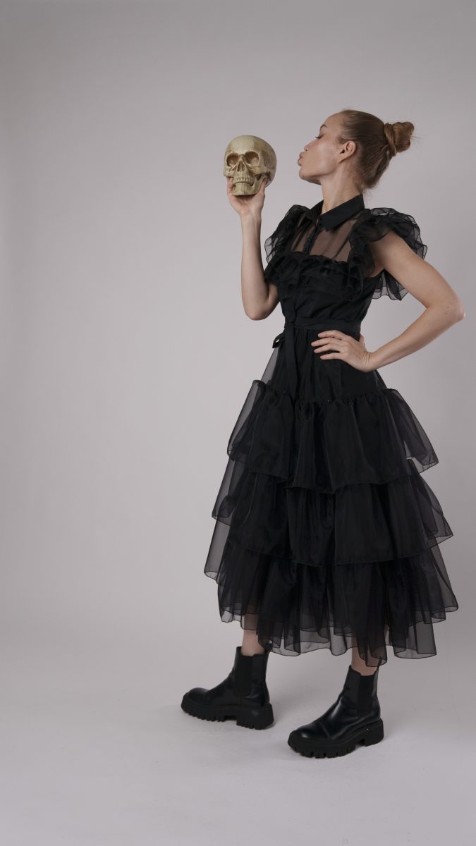 Side view of Nightshade gothic Halloween dress with layered black tulle, model playfully kissing skull prop.