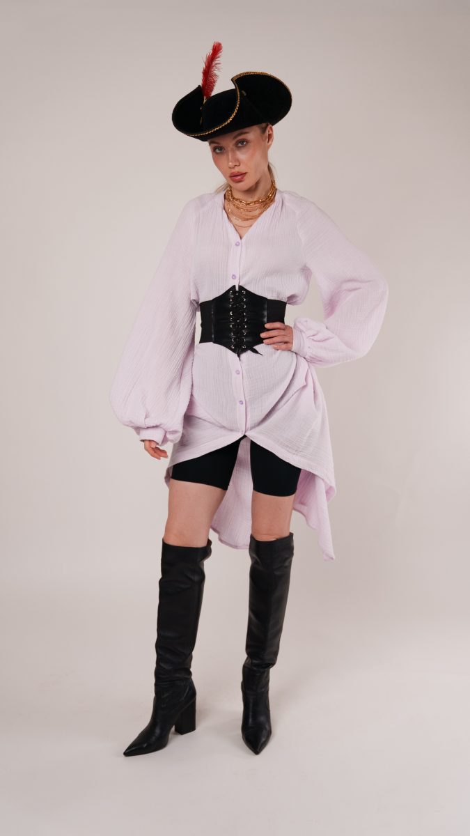 Model in a pirate-inspired Halloween costume featuring the Tundra Dress styled with billowing sleeves, a black corset belt, thigh-high black boots, and a black tricorn hat with a red feather.