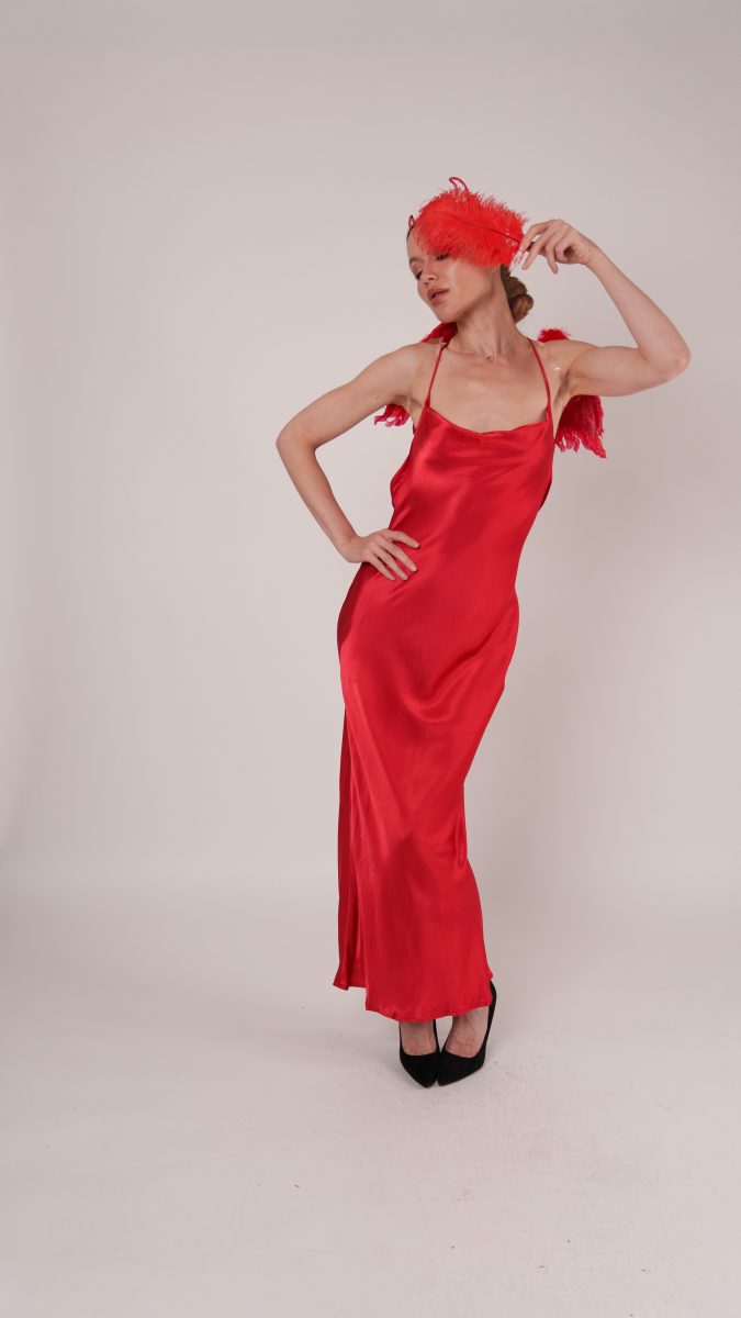 Woman in a red satin slip gown with feathered mask and wings, styled as a Devil Halloween costume idea using the Vixen Dress sewing pattern.