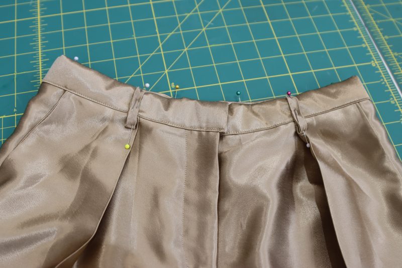How To Pin Sew Belt Loops To Wasitband - Satin - Mood Fabrics - Firenze Blouse Trousers Free Sewing Pattern Tutorial - MDF464 - Mood Fabrics Sewciety Blog - Pin and sew the belt loops to the waistband of the pants.