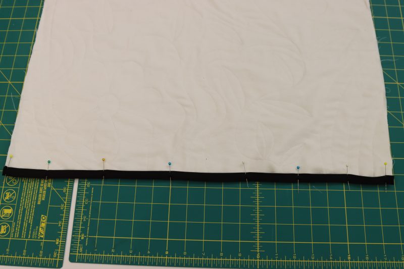 How To Pin Sew Bias Binding To Coat Back - Mercerized Organic Egyptian Cotton Voile - Mood Fabrics - Coeur D'Alene Coat Free Sewing Pattern Tutorial - MDF472 - Mood Fabrics Sewciety Blog - Pin and sew the bias binding to the bottom edge of the back coat piece.