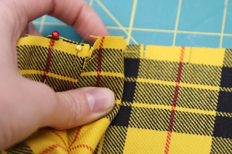 How To Pin First Pleat - Virgin Wool Twill - Mood Fabrics - Silverstone Mini Dress Free Sewing Pattern Tutorial - MDF489 - Mood Fabrics Sewciety Blog - Pin the first pleat in place and begin folding the one directly next to it.