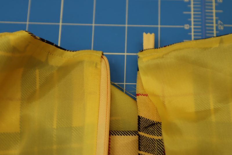 How To Tuck Zipper Tape Between Layers - Invisible Zipper - Mood Fabrics - Silverstone Mini Dress Free Sewing Pattern Tutorial - MDF489 - Mood Fabrics Sewciety Blog - Tuck the zipper tape into the wrong side of the dress between the lining and the main fabric.
