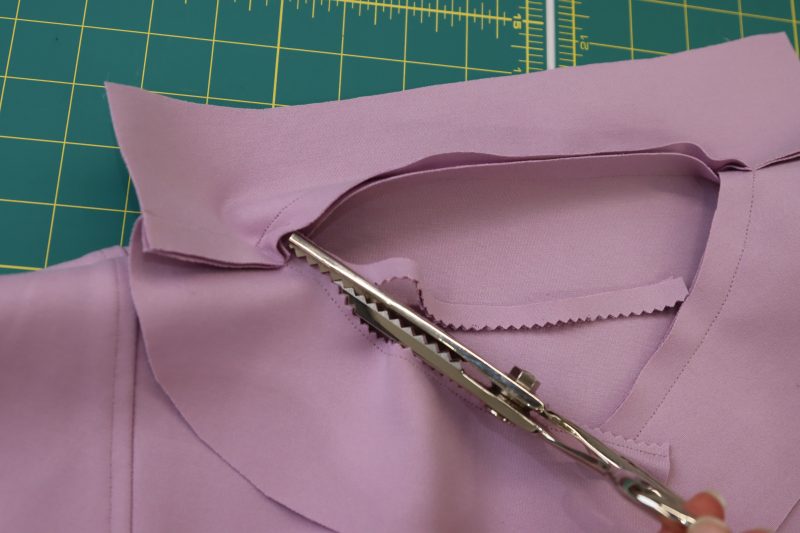 How To Trim Neckline Facing Seam Allowance - Stretch Ponte Knit - Mood Fabrics - Camarillo Cardigan and Magdalene Midi Skirt Free Sewing Pattern Tutorial - MDF490 - Mood Fabrics Sewciety Blog - Trim the neckline seam allowance with pinking shears to eliminate bulk.