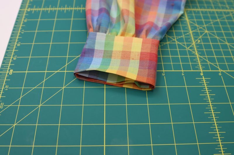 How To Fold Sleeve Cuff Raw Edges - Rainbow Checks Cotton Shirting - Mood Fabrics - Bayport Blouse Free Sewing Pattern Tutorial - MDF494 - Mood Fabrics Sewciety Blog - Fold and press the raw edges of the sleeve cuffs towards the inside of the blouse.Bayport Blouse Free Sewing Pattern Tutorial - MDF494 - Mood Fabrics Sewciety Blog - How To Fold Sleeve Cuff Raw Edges - Rainbow Checks Cotton Shirting - Fold and press the raw edges of the sleeve cuffs towards the inside of the blouse.