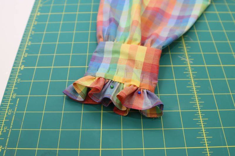 How To Pin Sleeve Ruffles To Cuffs - Rainbow Checks Cotton Shirting - Mood Fabrics - Bayport Blouse Free Sewing Pattern Tutorial - MDF494 - Mood Fabrics Sewciety Blog - Pin the sleeve ruffles in between the cuff pieces.