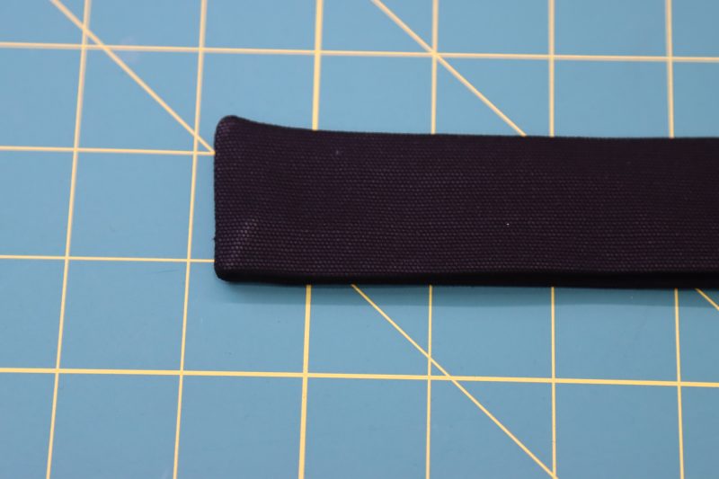 How To Press Waistband Raw Edges - Cotton Canvas - Mood Fabrics - Clarkston Carpenter Pants Free Sewing Pattern Tutorial - MDF503 - Mood Fabrics Sewciety Blog - Press the raw edges of the waistband towards the inside of the two pieces of fabric.