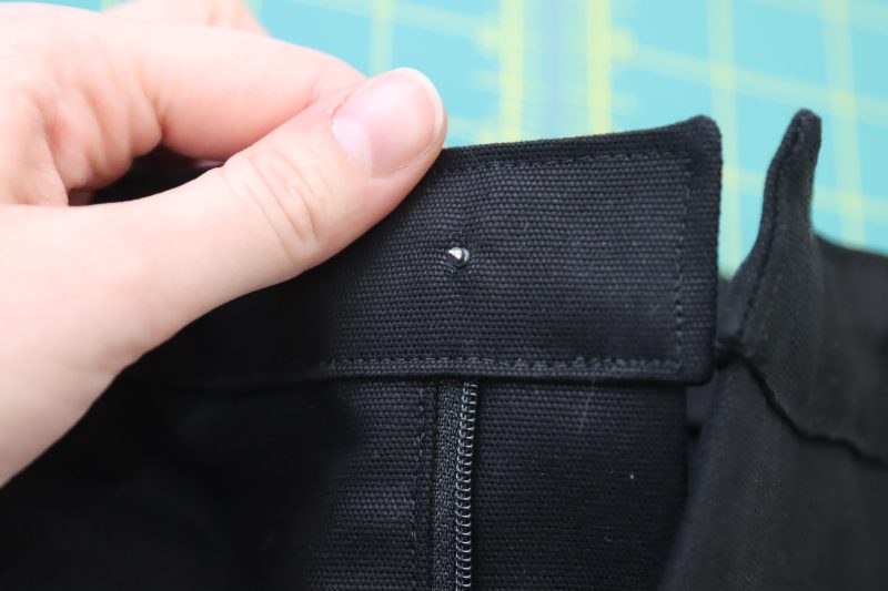 How To Place Button Backing Into Hole - Silver Jeans Button - Mood Fabrics - Clarkston Carpenter Pants Free Sewing Pattern Tutorial - MDF503 - Mood Fabrics Sewciety Blog - Place the button backing through the back of the hole.