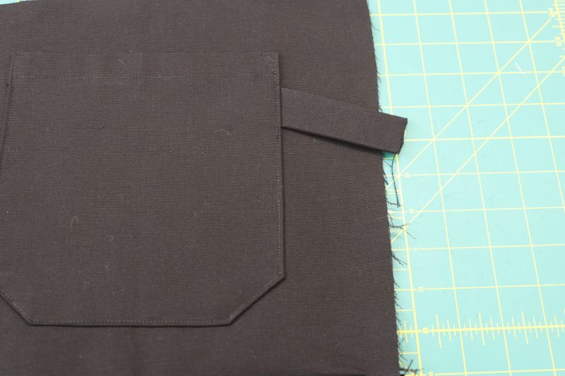 How To Insert Strap Under Back Pocket - Cotton Canvas - Mood Fabrics - Colfax Carpenter Pants Free Sewing Pattern Tutorial - MDF504 - Mood Fabrics Sewciety Blog - Insert the strap under the back right pocket.