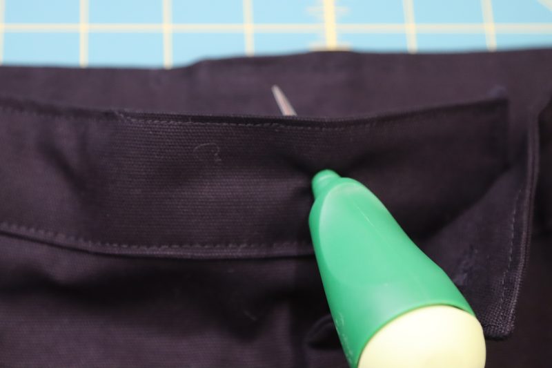 How To Insert Hole Into Waistband - Cotton Canvas - Mood Fabrics - Colfax Carpenter Pants Free Sewing Pattern Tutorial - MDF504 - Mood Fabrics Sewciety Blog - Poke a hole through the back overlapping waistband with an awl.