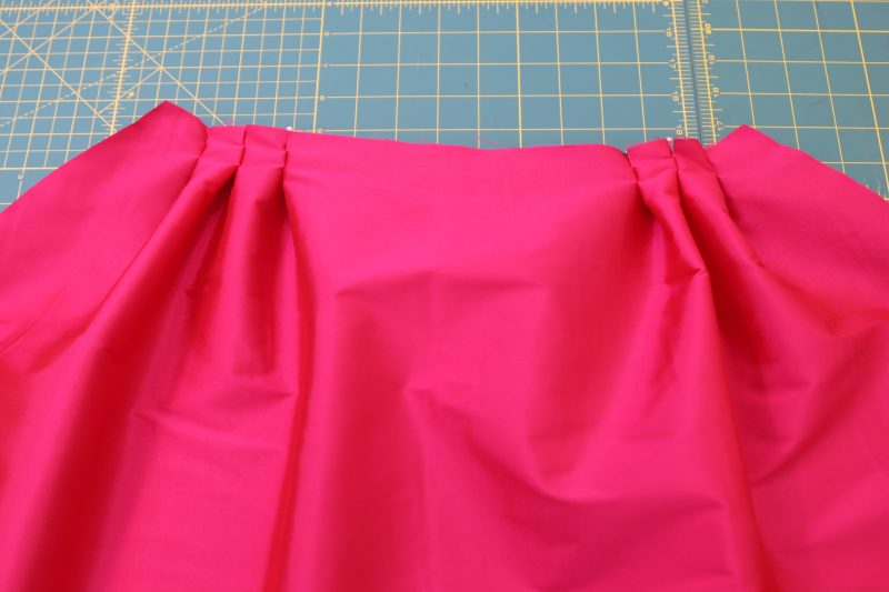 How To Pin Outer Skirt Pleats - Polyester Taffeta - Mood Fabrics - Biella Fit and Flare Dress Free Sewing Pattern Tutorial - MDF514 - Mood Fabrics Sewciety Blog - Pin the 6 pleats by bringing the notches together.