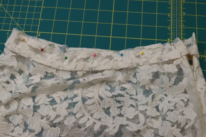 How To Pin Waistband To Skirt Waistline - Embroidered Lace - Mood Fabrics - Taiga Trapeze Skirt Free Sewing Pattern Tutorial - MDF512 - Mood Fabrics Sewciety Blog - Sandwich the skirt waistline inside of the waistband and pin.