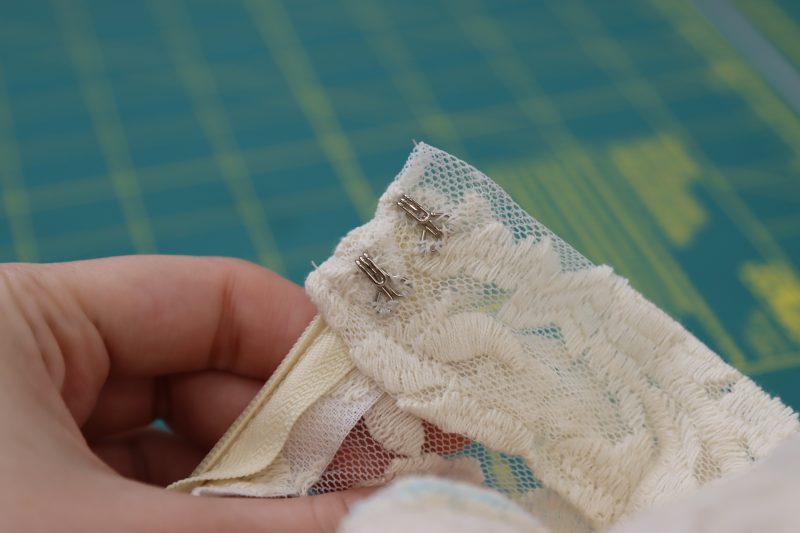 How To Sew Hook By Hand - Hooks And Eyes - Mood Fabrics - Taiga Trapeze Skirt Free Sewing Pattern Tutorial - MDF512 - Mood Fabrics Sewciety Blog - Hand sew the “hook” pieces of the hooks and eyes to the inside of the waistband.