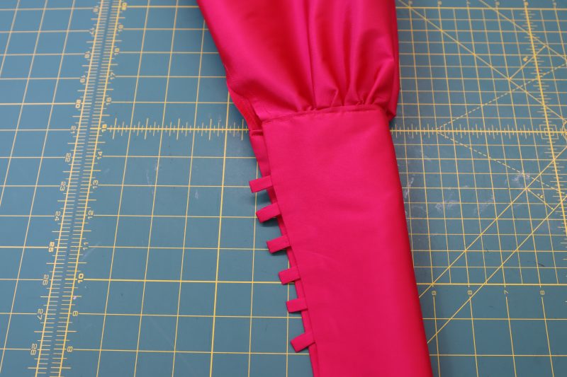 How To Topstitch Gathered Sleeve Into Cuff Opening - Polyester Taffeta - Mood Fabrics - Biella Fit and Flare Dress Free Sewing Pattern Tutorial - MDF514 - Mood Fabrics Sewciety Blog - Topstitch the cuff opening to secure the gathers.