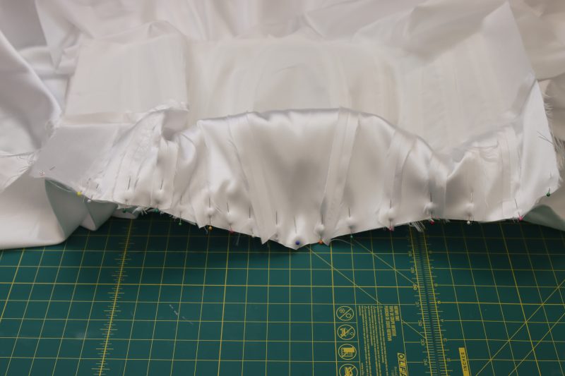 How To Pin Sew Pleated Skirt To Bodice - Polyester Mikado - Mood Fabrics - Selenite V Waist Ballgown Free Sewing Pattern Tutorial - MDF515 - Mood Fabrics Sewciety Blog - Pin and sew the pleated skirt to the outer bodice layer.